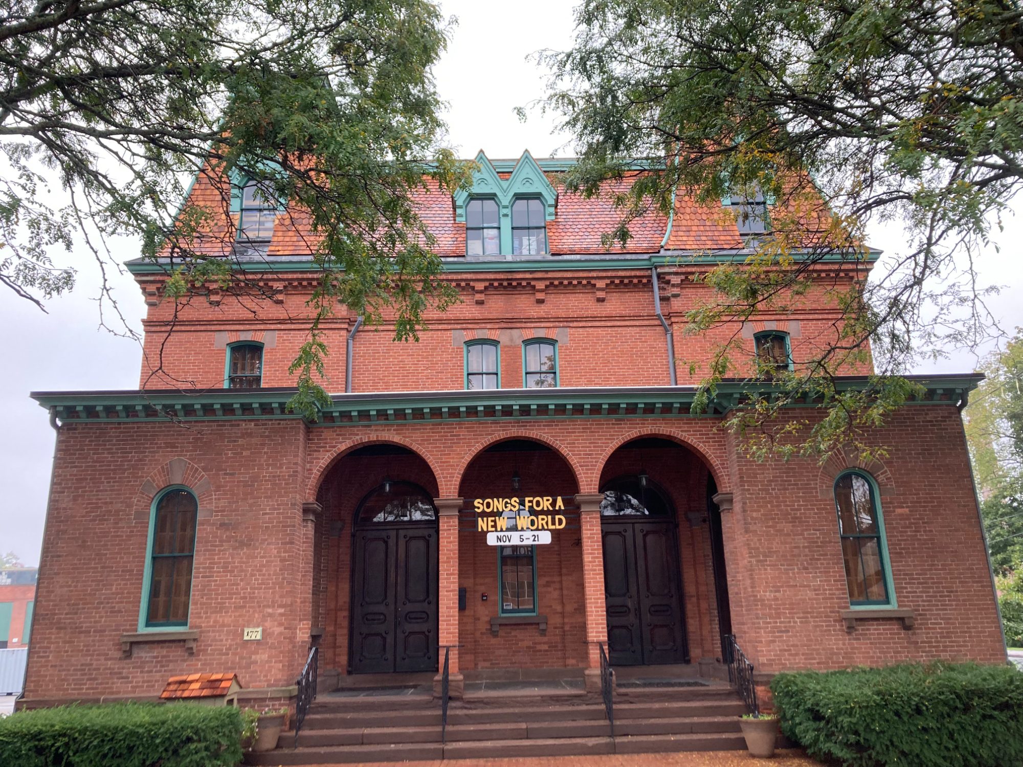 Cheney Hall's arched brick entrance and gabled front elevation beneath the new roof