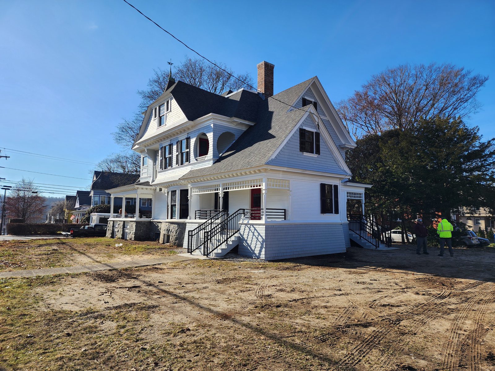Right elevation after restoration: new white clapboard and shingle siding, restored round attic window, rebuilt brick chimney and porch, with the site regraded