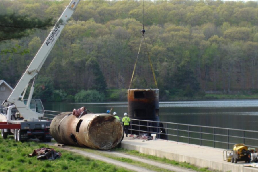 Crane setting a large steel cylinder at the Lake Watrous shoreline