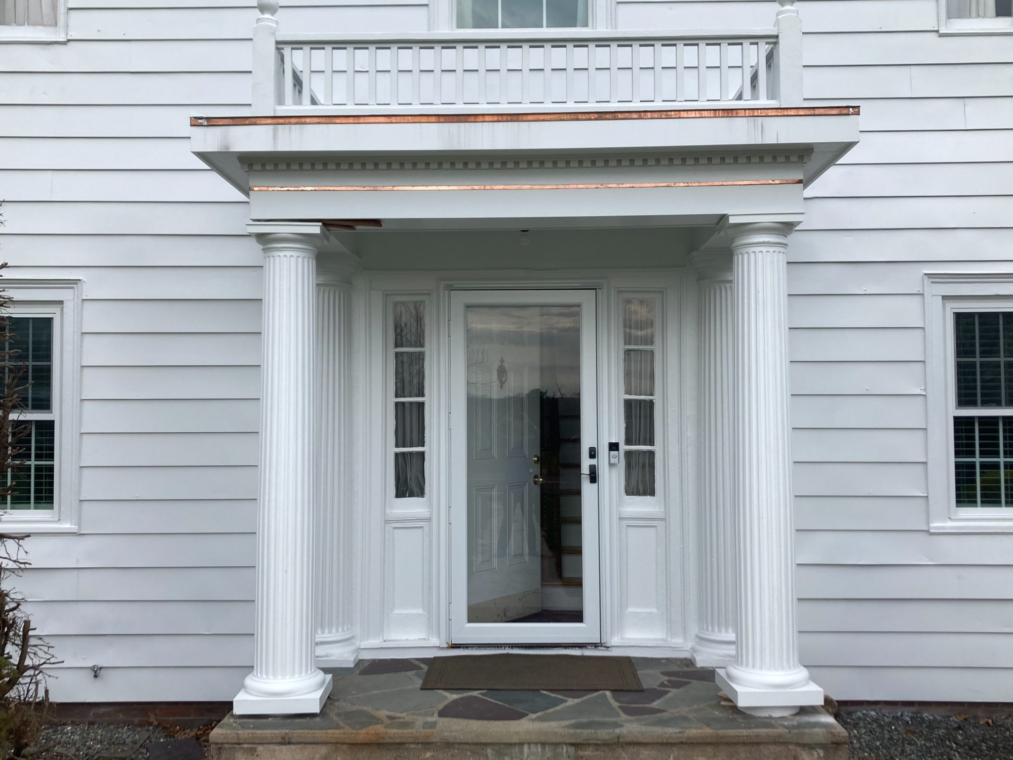 Restored front portico of the Wallingford mansion: new fluted columns, rebuilt porch framing, balustrade above, and new door and sidelights