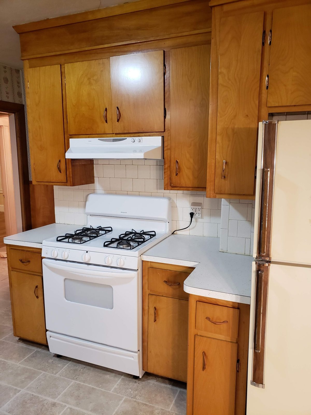 The original kitchen range wall with wood cabinets, square tile backsplash and laminate counters