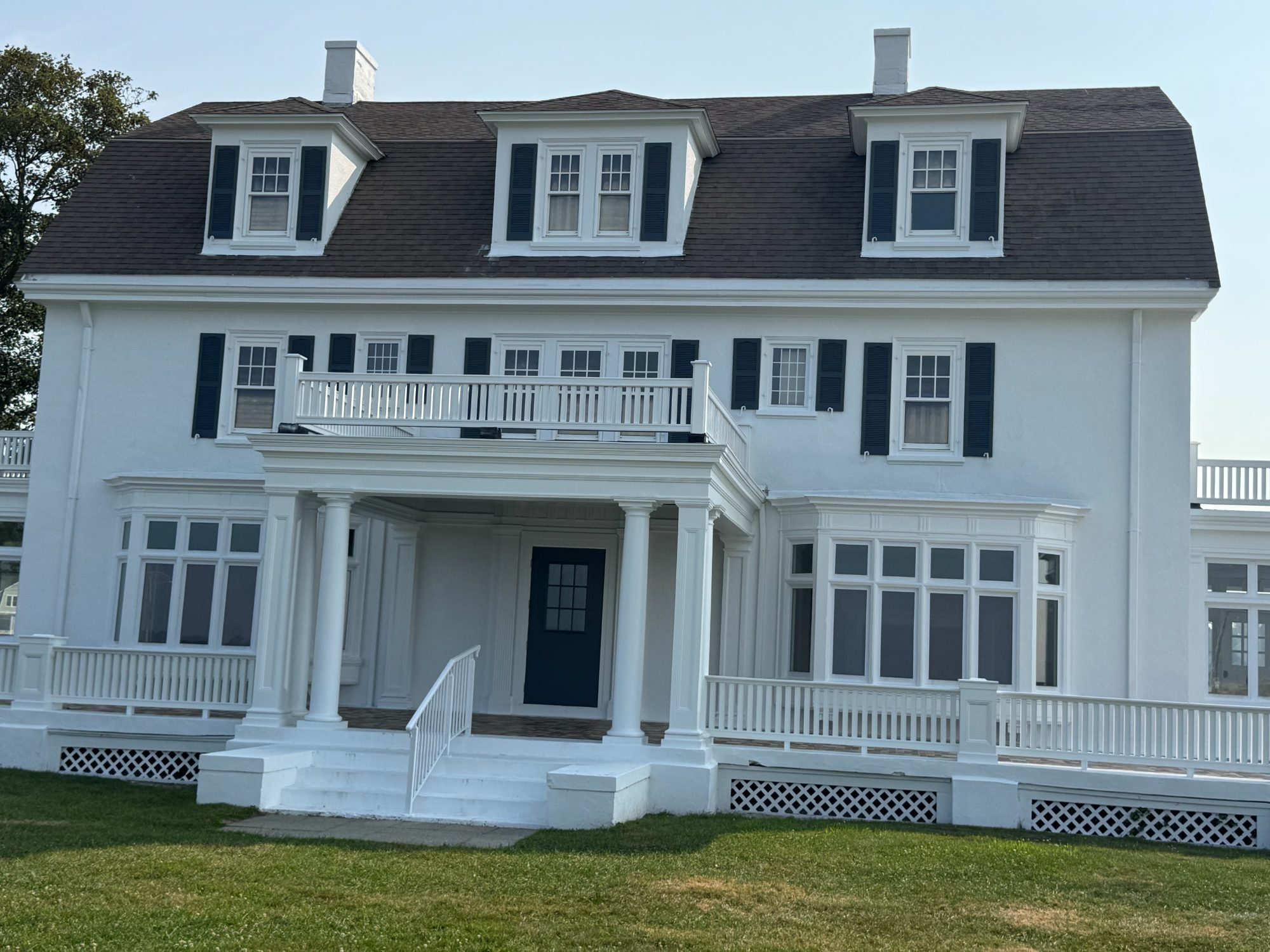 The restored Zbierski House at Eastern Point Beach, Groton: white three-storey house with dormers, rebuilt balcony, columns and porch railings