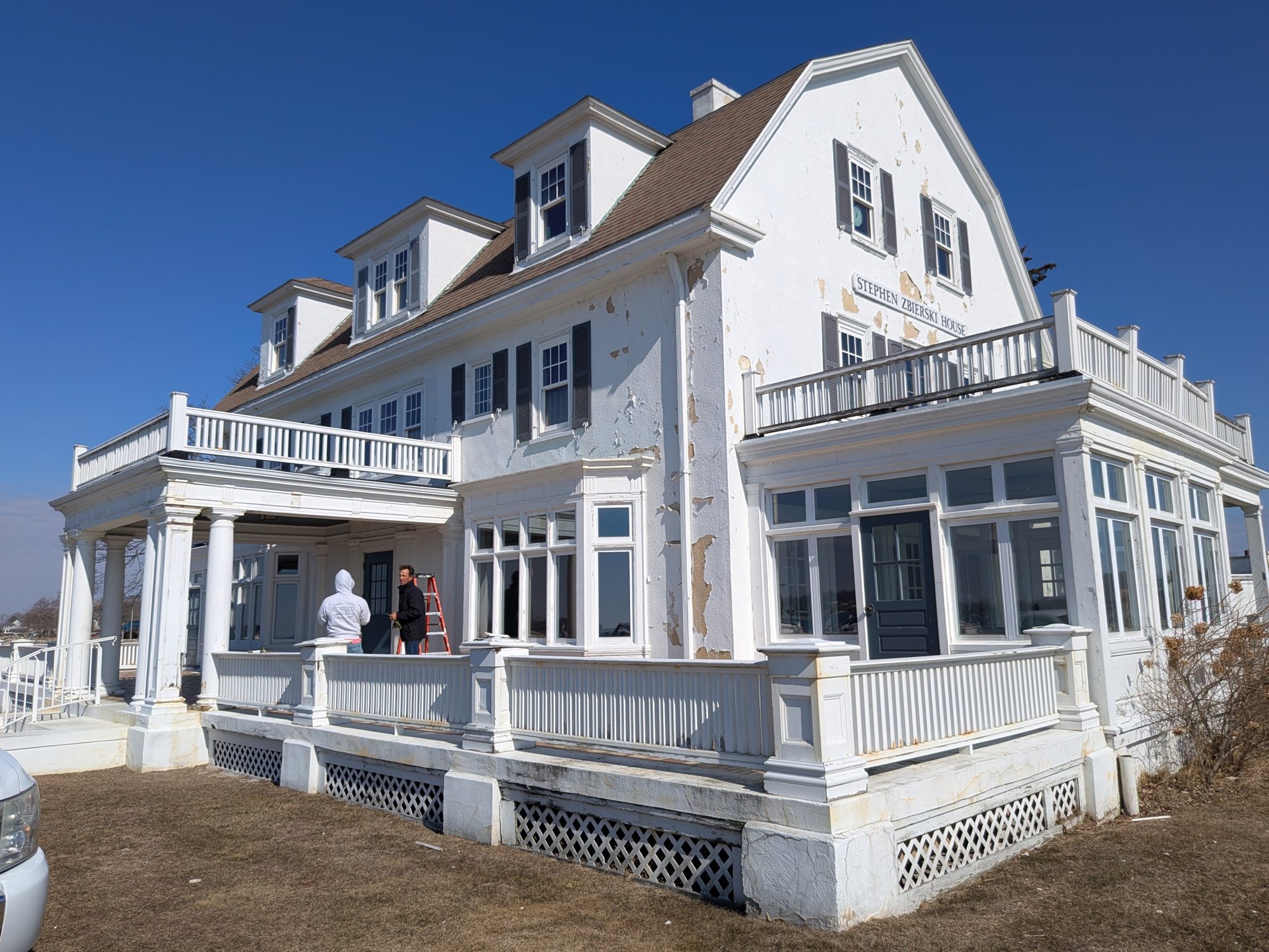 The Zbierski House gable end and sunroom before restoration, with paint and stucco coating peeling from the walls